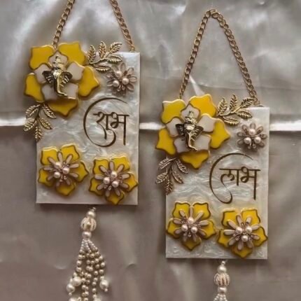 Handmade resin Shubh Labh wall hanging set with Lord Ganesha, yellow floral design and pearl tassels for home entrance decoration.