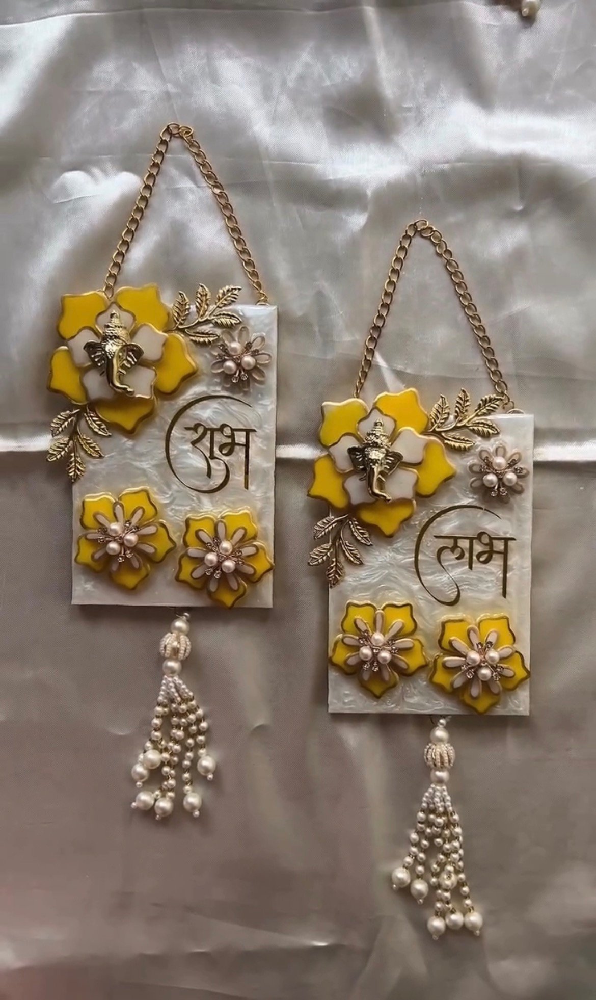 Handmade resin Shubh Labh wall hanging set with Lord Ganesha, yellow floral design and pearl tassels for home entrance decoration.