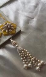 Close-up of pearl tassel detailing on handmade resin Shubh Labh wall hanging with premium decorative finish.